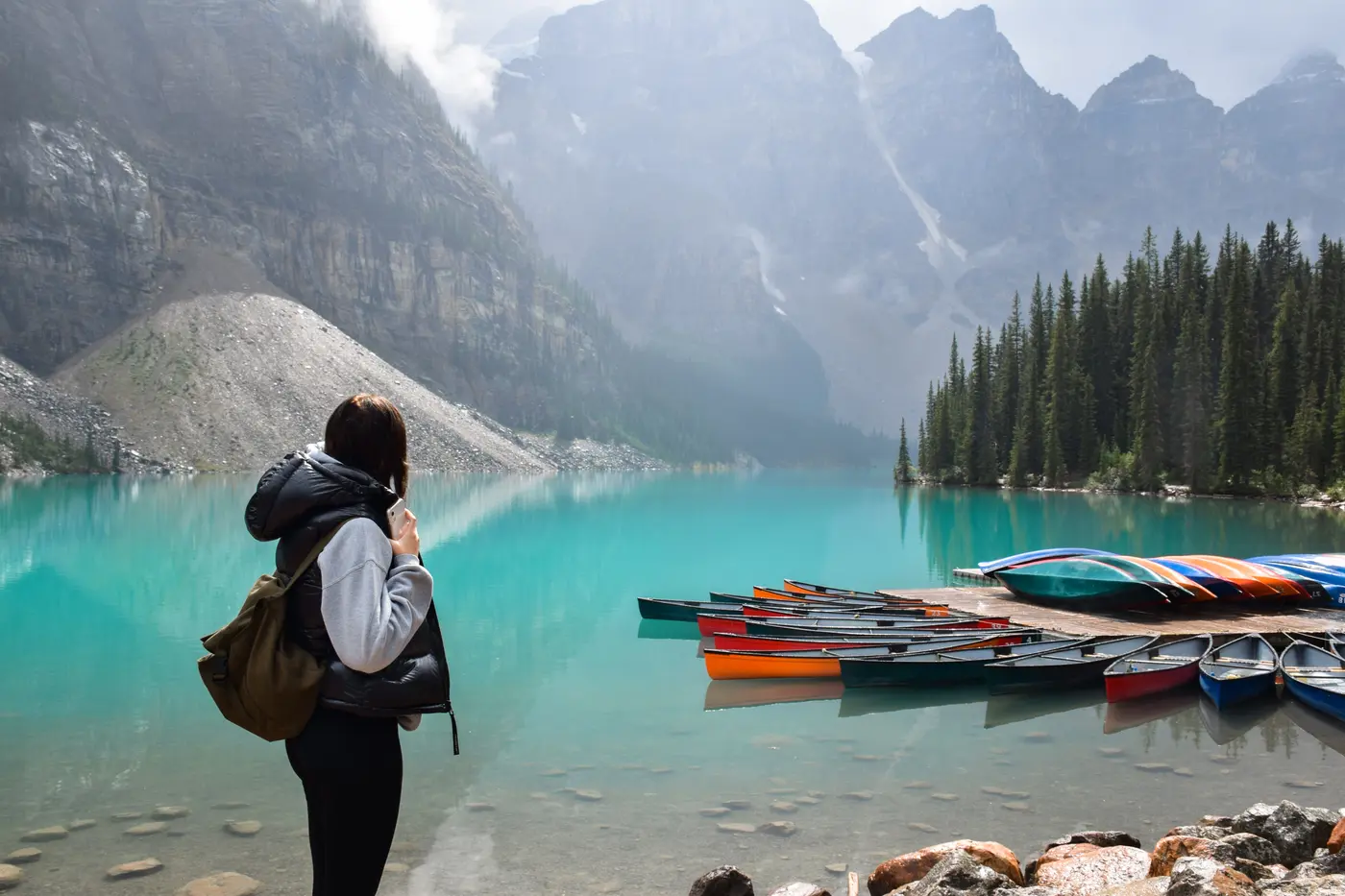 Viajante diante de lago com canoas